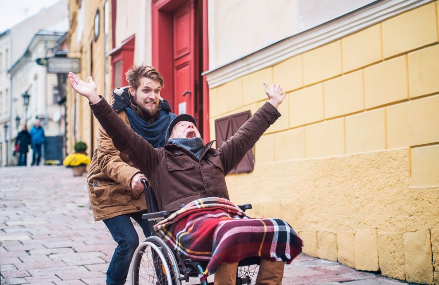 Senior Father In Wheelchair And Son, Both With Enthusiatic Expressions